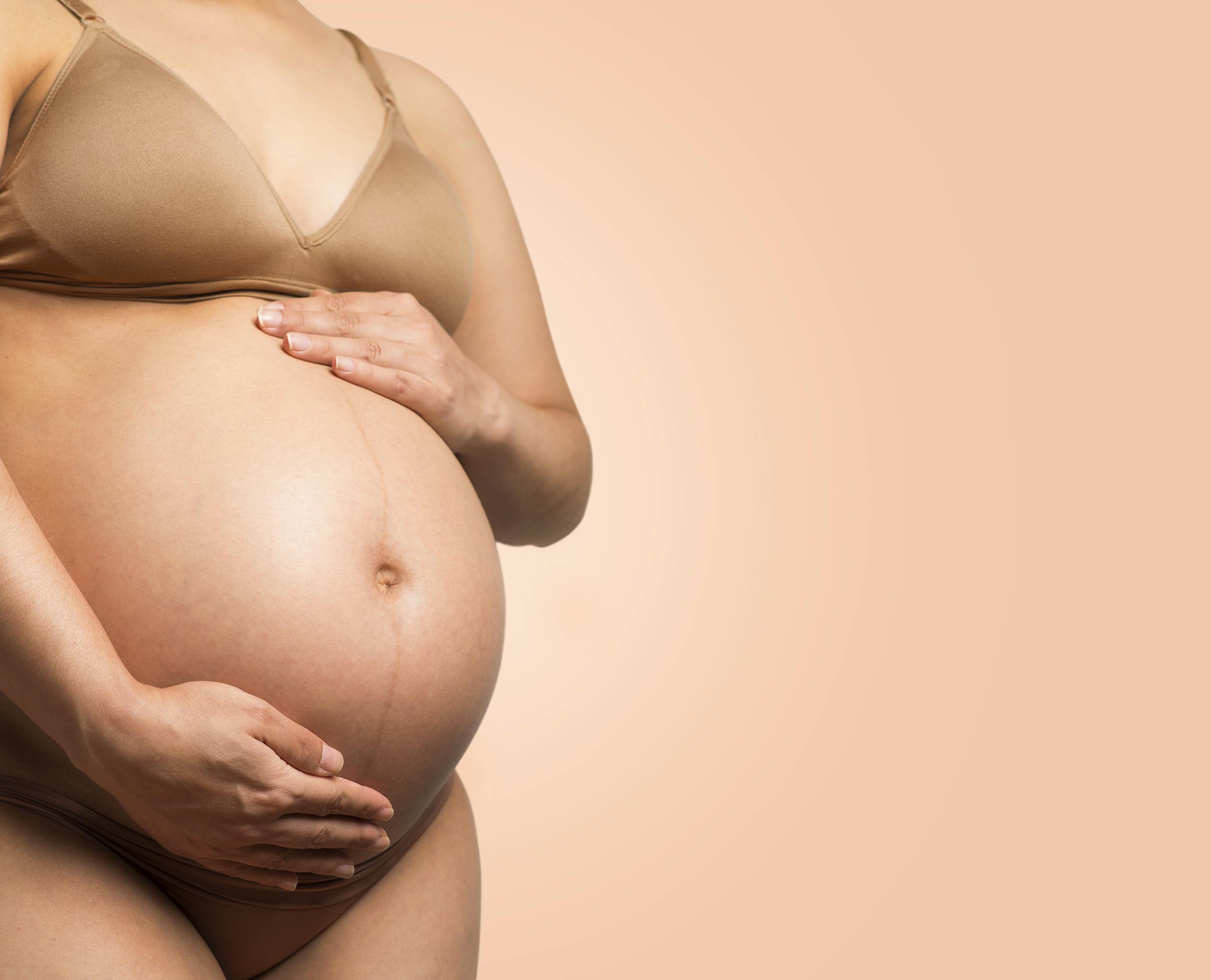 A pregnant woman gently cradles her belly, symbolizing motherhood and love.