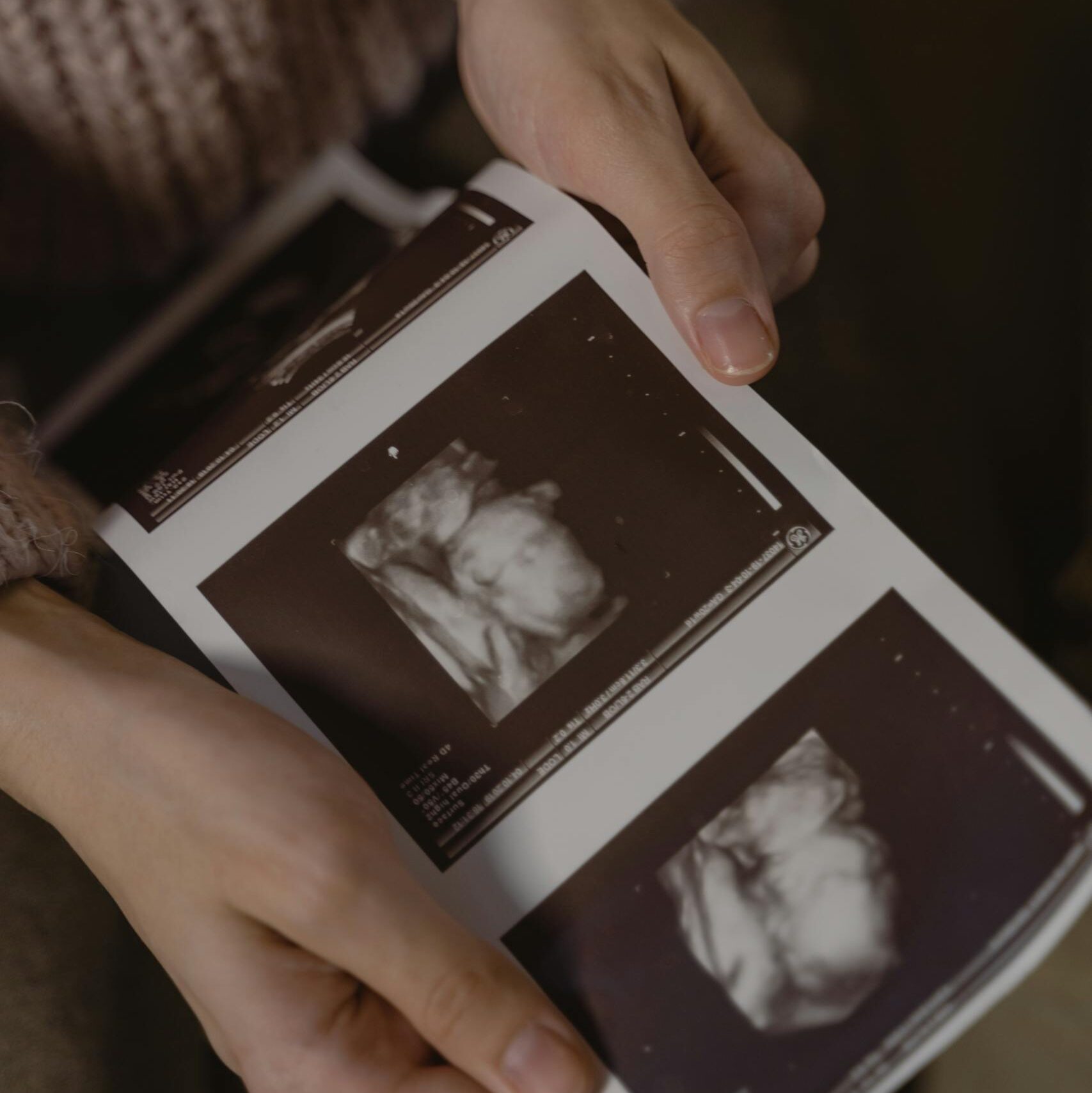 Hands gently holding ultrasound images, depicting a pregnancy moment.