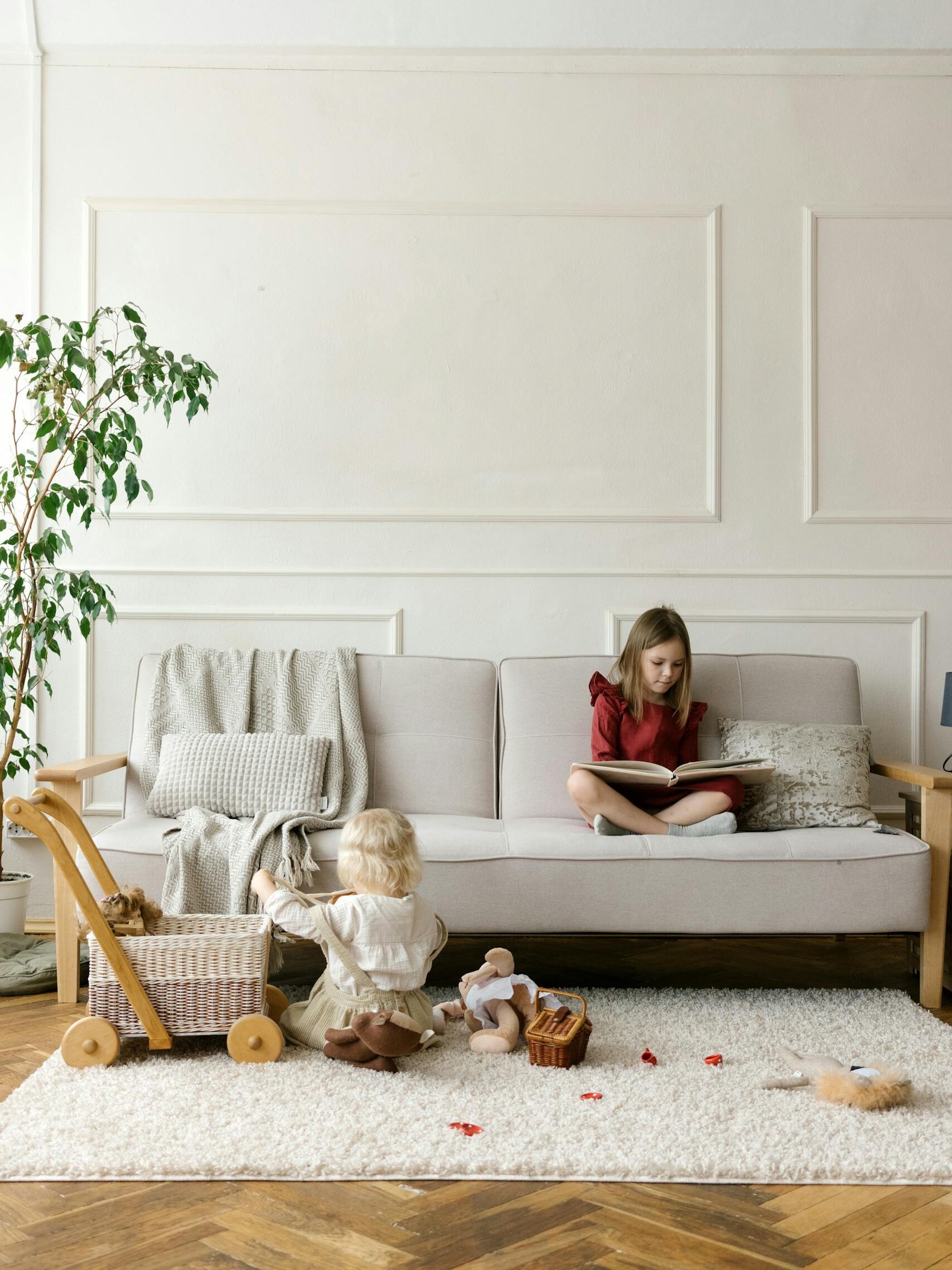 Two children playing and reading on a couch in a cozy living room setting.